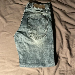 Blå jeans med klassisk passform - Snygga blå jeans med klassisk femficksdesign och diskret slitning på bakfickan. Jeansen har en rak siluett och är tillverkade i robust denim. Perfekta för dig som gillar en tidlös look.