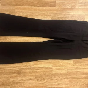 Svarta vida kostym byxor - Säljer ett par svarta kostym byxor med rak och vid passform. Byxorna har en klassisk look och är perfekta för dig som gillar en stilren och enkel stil. Materialet känns mjukt och följsamt, vilket gör dem bekväma att bära hela dagen.