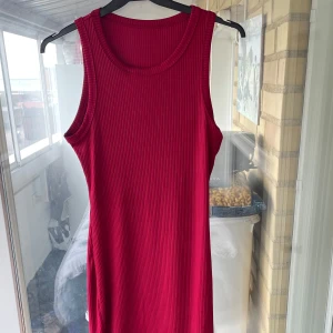 Ribbad röd ärmlös klänning från SHEIN - Ribbad röd klänning från SHEIN i storlek S. Ärmlös modell med rund halsringning och rak passform. Klänningen är knälång och tillverkad i mjukt, stretchigt material.