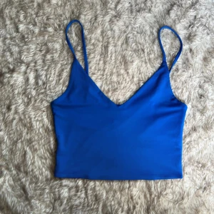 Blå topp från Amisu - Snygg blå topp från Amisu med smala axelband och v-ringning. Toppen är croppad och har en enkel, stilren design.