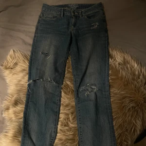 Blå slitna jeans från Esprit W26 - Snygga blå jeans från Esprit i rak modell med slitningar och hål på knäna. Klassisk femficksdesign, kontrastsömmar och dragkedja. Bakfickorna har dekorativa sömmar och jeansen har en cool, avslappnad vibe.