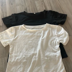 Svart och vit basic t-shirt - Två enkla t-shirts i svart och vitt med rund hals och korta ärmar. Modellen är klassisk och passar perfekt till jeans eller shorts. Materialet känns mjukt och skönt mot huden, troligtvis i bomull. Perfekt för en clean och stilren look.