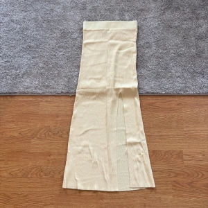 Gul ribbad långkjol från Dilvin - Säljer en gul ribbad långkjol från Dilvin. Kjolen har en rak passform med slits framtill och är tillverkad i ett mjukt stickat material. Står ej storlek, men är som en Xs/S