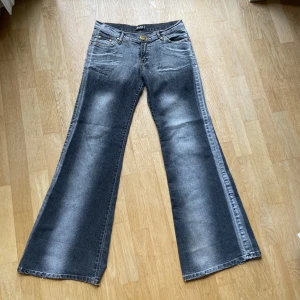 Bootcut jeans från Dolce & Gabbana - Snygga bootcut jeans från Dolce & Gabbana i tvättad grå denim med slitna detaljer och råa kanter. Klassisk femficksmodell med mässingsfärgade knappar och logga på både knapp och ficka. Perfekt för dig som gillar en cool och avslappnad stil.