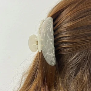 Vit hårklämma i marmormönster - Stilren vit hårklämma med marmorerat mönster som ger en fräsch och trendig look. Perfekt accessoar för att snabbt fixa frisyren och hålla håret på plats. Klämman har en mjuk, rundad form och är lätt att använda 🤍