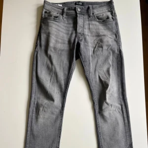 Grå slim fit jeans från Jack & Jones - Snygga grå jeans från Jack & Jones i slim glenn. Jeansen är snygga med det lätt tvättad looken framtill. Säljer för 250kr