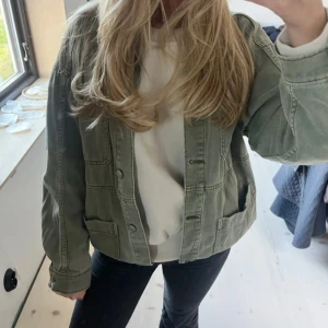 Grön jeansjacka  - Snygg ljusgrön jeansjacka från H&M Divided med klassisk krage, knappar framtill och flera fickor. Jackan har en loose passform och är tillverkad i bomull. Perfekt för dig som gillar en avslappnad och trendig stil.