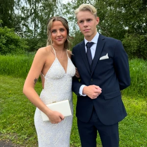 Vit glittrig långklänning med öppen rygg - Säljer nu min älskade balklänning🤍finns defekter på släpet då den har legat på kullerstenar men inget man tänker på när släpet ligger ner. Skriv om ni vill ha mer bilder💕Den kostar ca 6000kr nypris 
