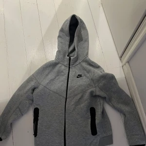 Grå Nike hoodie med dragkedja XL - Tja! Säker denna as feta grå nike tech fleecen. Det är den nya modellen. Den är väldigt skön och speciellt nu för hösten och vintern. Den är knappast använd. Nypris(1000kr) har ni någon fråga är det bara att skriva.!⭐️
