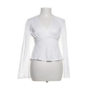 Vit omlottblus från Gina Tricot - Säljer en vit omlottblus från Gina Tricot i storlek S. Blusen har långa ärmar, v-ringning och knytband i midjan som ger en snygg siluett. Tillverkad i ett lätt och luftigt bomullstyg, perfekt för vår och sommar.