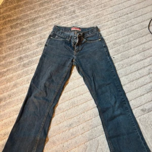 Blå jeans från ONLY bootcut - Snygga blå jeans från ONLY med klassisk bootcut-modell. Jeansen har fem fickor, kontrastsömmar och normal midja. Tillverkade i jeansmaterial med en lätt tvättad look och detaljerade bakfickor. Perfekta för en avslappnad stil.