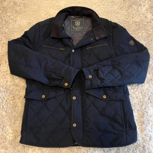 Mörkblå quiltad jacka från Bondelid - Snygg mörkblå quiltad jacka från Bondelid. Den är använd och har några defekter. Dragkedjan har lossnat lite längst ner och en tab har halvt lossnat. Hör gärna av er för fler bilder osv!