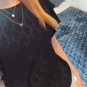 Svart blus med volangärm och struktur - Säljer en svart blus med korta volangärmar och diskret rutstruktur i tyget. Perfekt för dig som gillar stilrena och feminina detaljer. Den är från lindex, jag har knappt använt den 