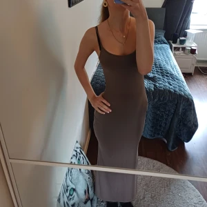 Brun långklänning från Zara - Säljer en snygg brun långklänning från Zara i storlek S. Klänningen har smala axelband. Den siter perfekt på kroppen och man ser kurvona.Materialet är mjukt och stretchigt, perfekt för dig som gillar långa tajta kläningar, och vill ha en enkel men elegant look.Den är tajt hela vägen till typ knäna sen blir den lite pösigare ❤️ hag vill sälja den för att jag tycker den är lite för kort på mig. Jag är 178 ❤️