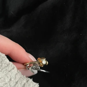 Unika ringar med handdesign - Två coola ringar i silver och guld med handformad detalj framtill. Båda ringarna har en liten rund sten som ger extra bling. Perfekt för dig som vill sticka ut med accessoarer som har en edgy vibe och snygga detaljer.
