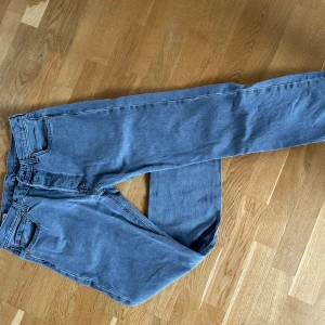 Levi's 501 blå jeans 32/32 - Klassiska Levi's 501 jeans i en snygg mellanblå tvätt. Rak passform med fyra fickor och ikonisk läderpatch bak i midjan. Jeansen har normalhög midja och är tillverkade i slitstarkt bomullsjeans. Perfekta för dig som gillar tidlös denimstil.