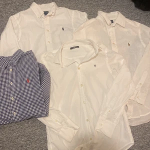Ralph Lauren & Replay skjortor, flera färger - 299kr st.Fyra skjortor i klassisk stil, tre vita från Ralph Lauren och Replay med broderad logga, samt en blåvitrutig från Ralph Lauren med röd logga. Alla har knappar framtill och lång ärm. Perfekt för dig som gillar stilrena och tidlösa plagg. 299kr st