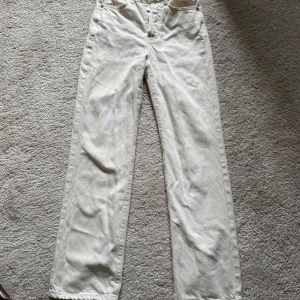 Straight Jeans Bikbok - Säljer ett par snygga vita jeans från Never Denim i modellen Regular Wide. Byxorna har hög midja, raka och vida ben samt klassiska femficksdetaljer. Tillverkade i kraftigt jeanstyg som ger en clean och fräsch look.