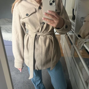 Beige kappa med bälte - Snygg beige kappa med knappar och knytbälte i midjan från Zara.