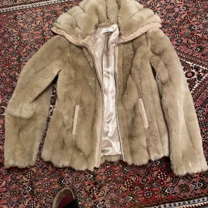Beige pälsjacka från Milla - Säljer en fluffig beige pälsjacka från Milla i storlek S. Jackan har mjukt foder, dragkedja framtill och två fickor. Perfekt för dig som gillar en lyxig och cozy vibe under höst och vinter. Jackan har lång ärm och en snygg krage.