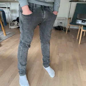 Replay grå slim jeans - Säljer ett par gråa Replay jeans med snygg tvätt och klassiska fem fickor. Modellen har slim passform och raka ben, med Replay-logga på bakfickan och svarta detaljer vid midjan. Perfekt för dig som gillar stilrena och moderna jeans. Aldrig andvänt, pris kan diskuterad.