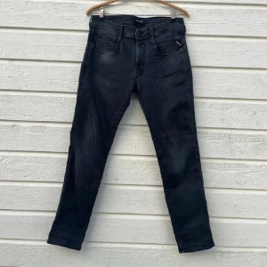 Svarta Replay anbass, waist 31/30 - Snygga svarta jeans från Replay med klassisk femficksdesign och raka ben. Jeansen har en mörk tvätt och diskreta sömmar, vilket ger en clean look. Passar dig som gillar stilrena och tidlösa jeans med bekväm passform.