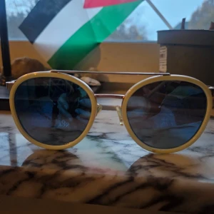 Runda solglasögon från Future - Snygga runda solglasögon från Future med svensk design. Glasen är mörka och ramen är ljusgul med tunna metallbågar. De har en cool dubbelbrygga och näskuddar för extra komfort. Perfekt accessoar för att lyfta din stil under soliga dagar.