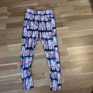 Färgglada mönstrade leggings 13-14 - Säljer ett par leggings med coolt randigt mönster i blått, rött och vitt. De har en tight passform och är perfekta för träning eller chill. Materialet är mjukt och stretchigt, vilket gör dem riktigt sköna att ha på sig.