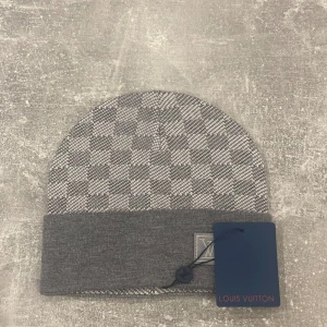 Grå mössa  - Snygg grå mössa som jag fick i present med klassiskt rutigt mönster och uppvikt kant. tillverkad i mjukt material som håller dig varm och stilren.