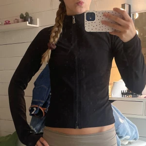 Svart tight zip-tröja med hög krage - Svart långärmad zip-tröja med hög krage och figurnära passform. Tröjan har dragkedja hela vägen framtill och är gjord i ett stretchigt, mjukt material som passar perfekt till träning eller chill. Enkel och stilren design utan synliga loggor.