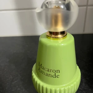 Macaron Amande parfymflaska - Snygg parfym i unik grön flaska med cool design.  Luktar krämig pistasch och vanilj. Perfekt för dig som vill sticka ut och addera något annorlunda till din samling. Märket och volymen syns inte, men flaskan är ett blickfång i sig.