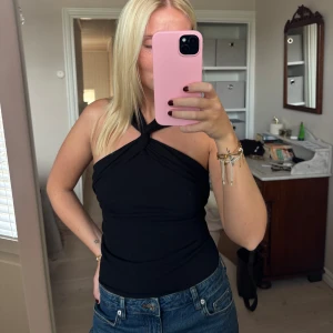 Svart omlott topp - Säljer en svart omlott topp med halterneck och twistad detalj framtill. Super fin och helt nytt skick!! 