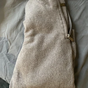 Beige halvzip-tröja från Stenströms - Snygg beige stickad tröja från Stenströms med half zip-dragkedja och ribbad krage. Perfekt för lager-på-lager och passar till både jeans och chinos. Mjuk och skön känsla tack vare det stickade materialet.