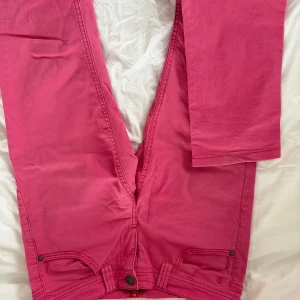 Rosa raka byxor från Esprit - Snygga rosa byxor från Esprit i slim fit-modell men skulle säga att det sitter rakt. De har fem fickor, dekorativ söm på bakfickan och klassisk knappstängning. 
