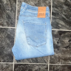Replay Anbass jeans  - Replay Anbass jeans i ljusblå tvätt med slitningar och snygga detaljer på bakfickorna. Slim fit-modell med klassisk femficksdesign och stretchigt material för skön passform. JAG SKICKAR EJ FLER BILDER NÄR JAG BÄR JEANSEN! för storleksguide hänvisar jag till måtten och för bättre inblick i passformen rekommenderar jag att googla på modellnamnet. Jeansen kan vara uppsydda utan att jag noterat det så kolla måtten noggrant :) Midja 39cm, längd 112cm. 38
