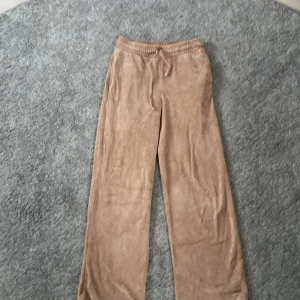 Beiga mjukisbyxor med snörning - Säljer ett par beiga mjukisbyxor från C i storlek 134/140. Byxorna har en skön loose passform, elastisk midja med snörning och praktiska sidofickor. Materialet är mjukt och känns riktigt chill mot huden, perfekt för att hänga hemma eller dra ut med kompisarna.