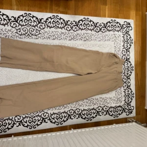 Beige mjukisbyxor från Bik Bok - Säljer ett par beige mjukisbyxor från Bik Bok i storlek S. Byxorna har elastisk midja och är tillverkade i mjukt material som är perfekt för chill dagar. Passformen är loose och färgen är neutral, vilket gör dem enkla att matcha med andra plagg.