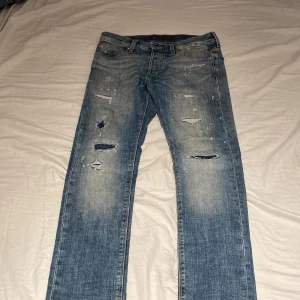 Slim fit jeans från Jack & Jones - Snygga blå jeans från Jack & Jones med slim fit och slitna detaljer. Modellen heter Glenn och har klassisk femficksdesign, med coola slitningar och tvättade partier för en avslappnad vibe. Perfekta för dig som gillar streetstyle och vill ha en modern look. W29 L30