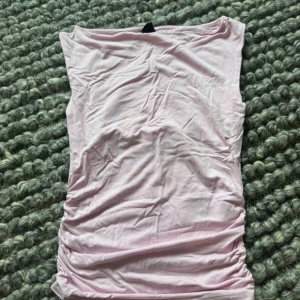 Ljusrosa tubtopp från Gina Tricot - Säljer en ljusrosa tubtopp från Gina Tricot i mjuk bomull. Toppen är enkel och stilren, perfekt att matcha med jeans eller kjol. Den är ärmlös och har en klassisk bandeau-form som sitter snyggt på kroppen.