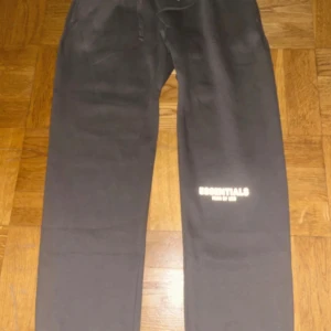 Grå Essentials mjukisbyxor Fear of God - Snygga grå mjukisbyxor från Essentials Fear of God med logga på benet och bakficka. Byxorna har elastisk midja och är tillverkade i mjukt bomullsmaterial. Perfekta för en chill och avslappnad stil. Kom gärna med prisförslag. 100% Bomull.