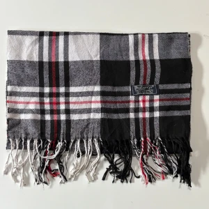 Rutig halsduk från Burberry - Snygg halsduk från Burberrys i 100% kashmir med klassiskt rutigt mönster i svart, vit, grå och röd. 