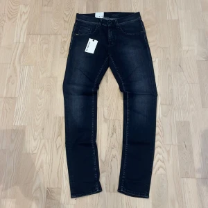 Helt nya Slim jeans från Tiger of Sweden - Snygga slim fit jeans från Tiger of Sweden i mörkgrå tvätt. Tillverkade med italiensk Candiani denim, och har diskreta slitningar och svarta nitar. Perfekt passform och stilren look för dig som gillar lite smalare modeler och känslan av helt nya fräsha jeans.