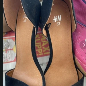 Svarta pumps från H&M, storlek 37 - Snygga svarta pumps från H&M i storlek 37. Skorna har en elegant design med spetsig tå och klack, perfekta för att lyfta din outfit. Utsidan är i svart material och innersulan är beige för en stilren kontrast.