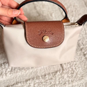 Beige handväska från Longchamp - Används en gång så i ny skick , kortet och påsen kvar jag säljer den eftersom jag har en annan färg som jag använder mest. Jag har strap som jag köpte från Amazon då väskan kommer utan strap 