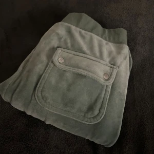 Gröna mjukisbyxor Juicy Couture XS - Inga slitningar, som nya✨ Snygga gröna mjukisbyxor från Juicy Couture i storlek XS. Byxorna har bred resår med snörning i midjan, stora fickor fram och bak med tryckknappar. Mjukt velourmaterial som är superbekvämt och chill. Perfekt för en laidback stil.