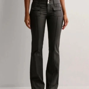 Svarta bootcut byxor med fickor - Ett par jeans som har ett typ skin material, alltid slutsålda eller så har de slutat säljas. Storlek 38. De är använda max 4 gånger och sen laget längst ner i en låda så de är ganska skrynkliga men de blir nog normala igen efter några användningar eller om man stryker💞 