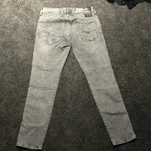 Replay Hyperflex Anbass grå jeans - Pris kan diskuteras. Säljer ett par Replay Hyperflex Anbass jeans i grå tvätt med snygga raka ben och klassiska fem fickor. Stretchigt material för extra komfort och cool Replay-logga på fickan. Passar dig som gillar stilrena och moderna jeans med smal passform.