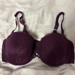 Mörkröd spets-bh från H&M 80D - Säljer en mörkröd bh från H&M i storlek 80D. Bh:n har vacker spetsdetalj över kuporna och justerbara axelband. Kuporna är formade och har snygg snörning framtill. 