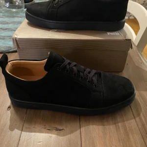 Svarta sneakers från Christian Louboutin - Snygga svarta sneakers från Christian Louboutin med klassisk röd sula och diskret logga undertill. Skorna är strolek 46 men passar 45 också. Skorna är lite använda men inget man tänker på. Det kommer med allt orginalt. Priset är inte fast och de är bara att höra av vid några funderingar