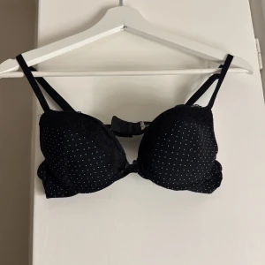 Mörkblå prickig bh med spets - Mörkblå bh med tunna axelband och vadderade kupor. Prickigt mönster över hela och dekorativ spets upptill. ⭐️⭐️